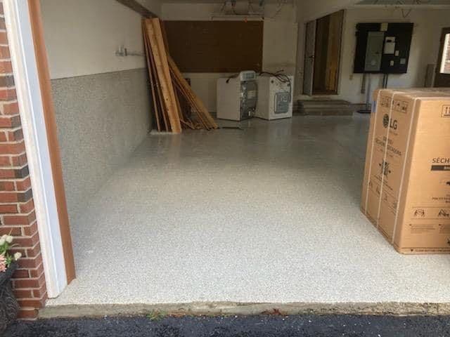 Garage interior with a newly installed speckled epoxy floor and cardboard boxes.