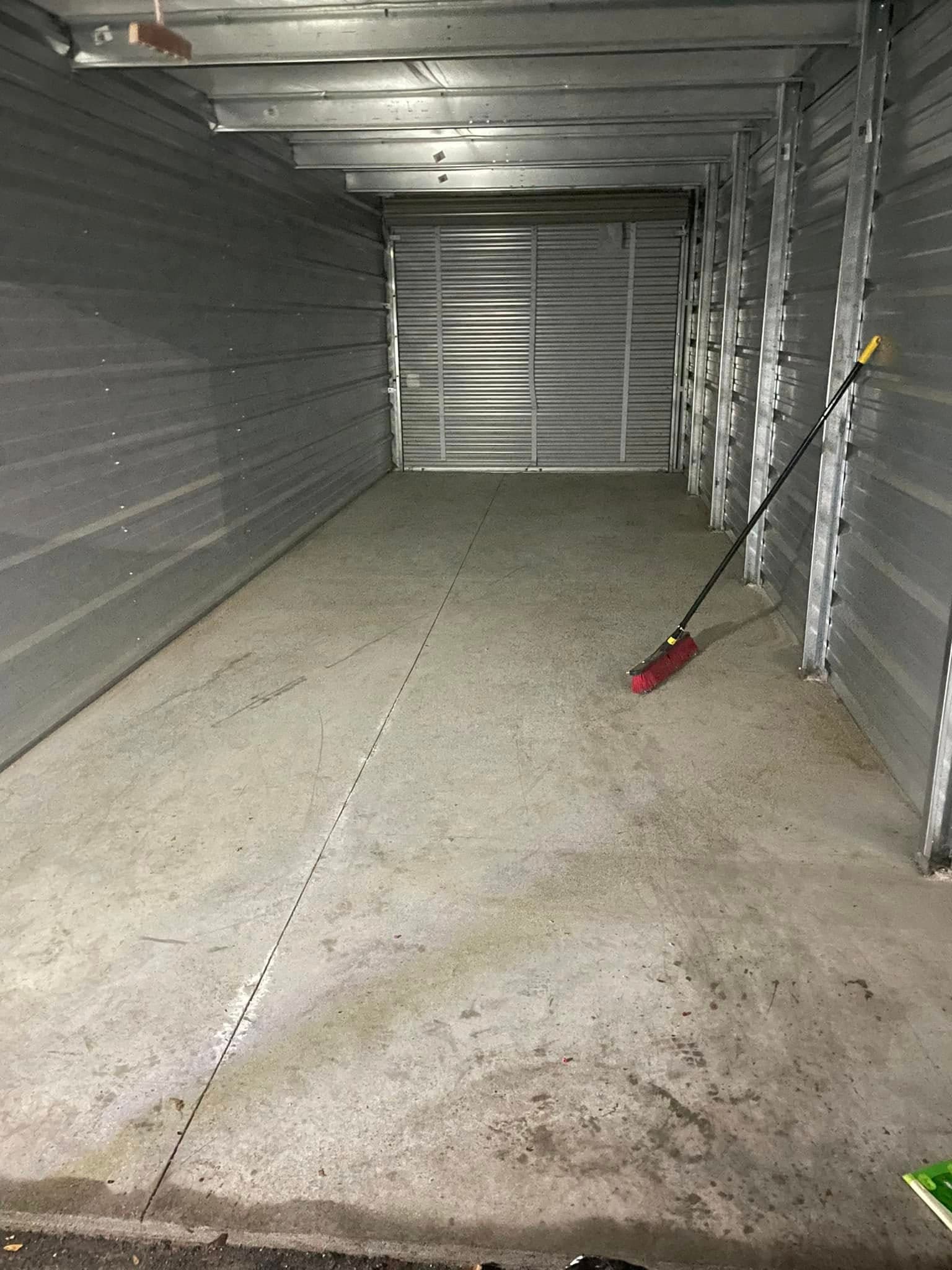 Empty storage unit with metal walls and broom leaning against the side.